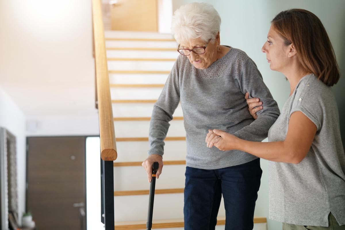 Senior Home Care Caregiver helping old lady with a cane